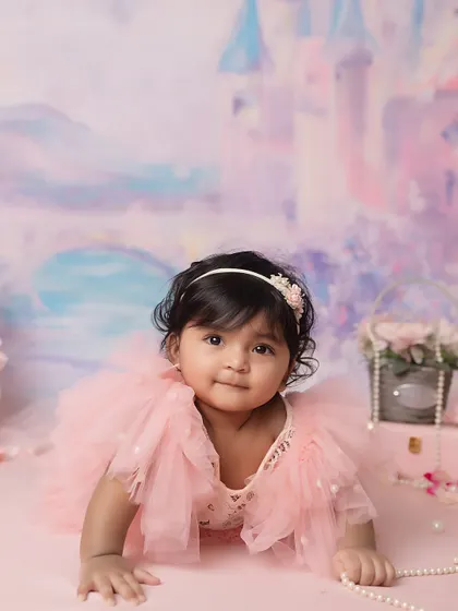 A curious gaze. This little girl, surrounded by pearls and pink, looks directly at the camera, creating a captivating portrait.