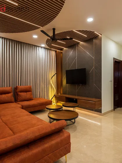 A bold and contemporary living room featuring a dark textured TV wall with geometric inlays. The circular wooden ceiling panels with integrated lighting create a dramatic and unique effect.