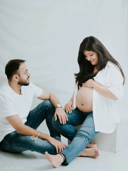 Sharing a smile in the studio. This candid moment from a couple's maternity shoot shows the fun and easygoing atmosphere I create.
