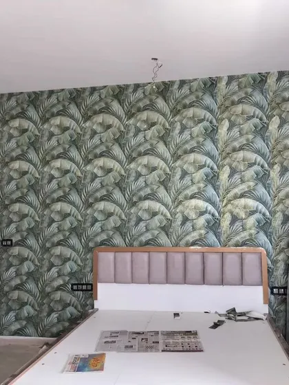 A bedroom with a bold tropical leaf wallpaper. The large-scale pattern makes a strong statement and creates a lush, jungle-like feel.