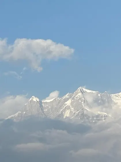 A glimpse of the majestic Himalayan peaks peeking through the clouds, as seen on our Deoriatal trek. These are the views that make the journey unforgettable.