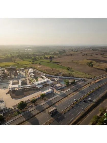 An aerial shot showing the temple complex's strategic location next to the highway, making it an accessible spiritual landmark for travelers and the local community.