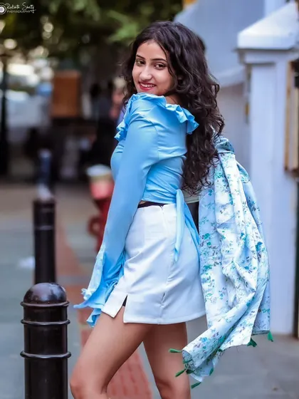 A playful, over-the-shoulder shot from a street photography session. The model's smile and the bright colors create a fun and energetic vibe.