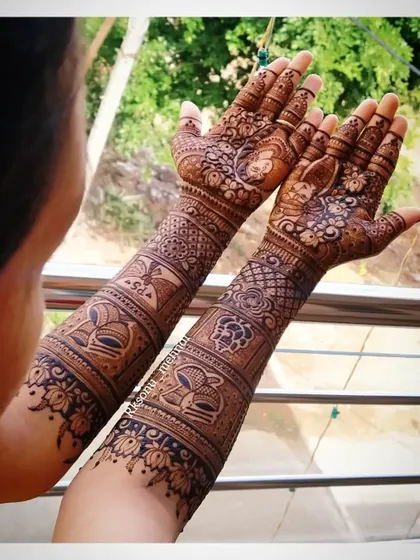 A beautiful shot of the bride displaying her full-arm mehndi. The design is rich with traditional figures and patterns, creating a stunning visual for her wedding day.