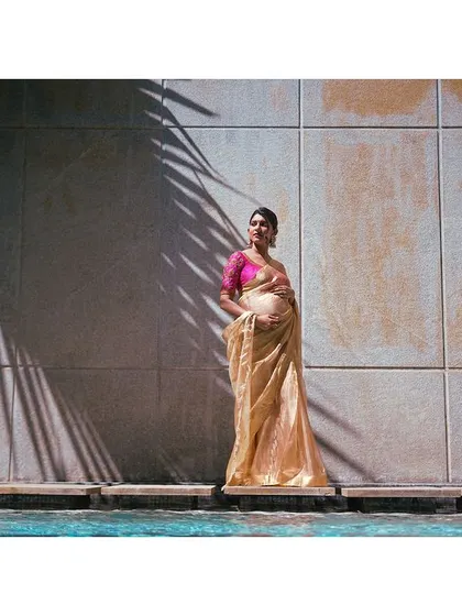 A high-fashion maternity shot. The play of light and shadow, the elegant saree, and the poolside setting combine to create a striking and artistic portrait.