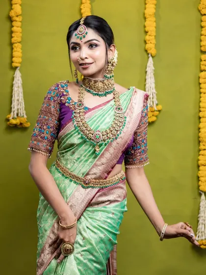 A lovely look from a makeup artist collaboration. The model is wearing a Victorian-style set with green stones that looks beautiful with her pastel green saree.