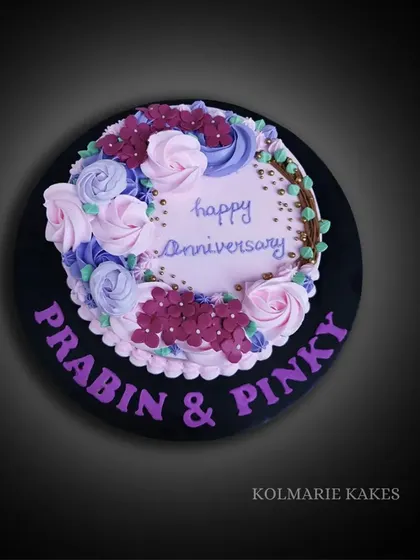 A lovely anniversary cake with a wreath of buttercream flowers. This strawberry cake is decorated with pink and purple roses and hydrangeas, perfect for a sweet celebration.