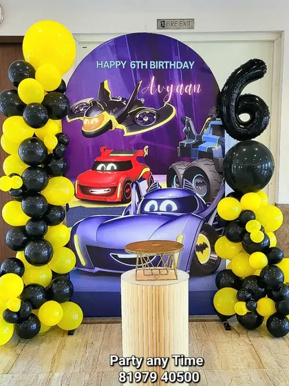 A creative Batman and Cars crossover theme for a 6th birthday, with a custom backdrop and a yellow and black balloon arrangement.