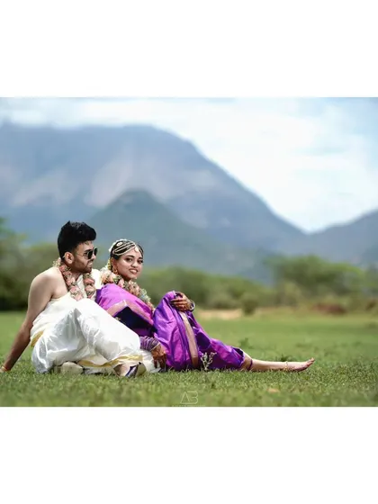 A post-wedding shoot that feels like a scene from a South Indian film. The couple is relaxed and happy, enjoying a quiet moment together in traditional attire against a scenic mountain view.