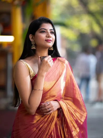Enjoying a cup of filter coffee while wearing a shimmering tissue saree. This lifestyle shot combines the elegance of the attire with a quintessential Bangalore experience.
