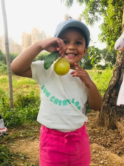 A young girl shows off a lemon she found on one of our trees. Our farm showcases a variety of fruit plants, offering more for kids to see and learn about.
