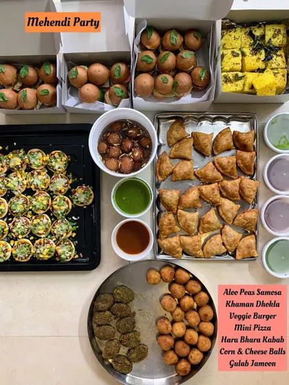 A vibrant and delicious spread of party starters for a Mehendi celebration. This order included crowd-pleasers like Aloo Peas Samosas, Khaman Dhokla, Mini Veggie Burgers, Mini Pizzas, Hara Bhara Kebabs, Corn and Cheese Balls, and sweet Gulab Jamun.