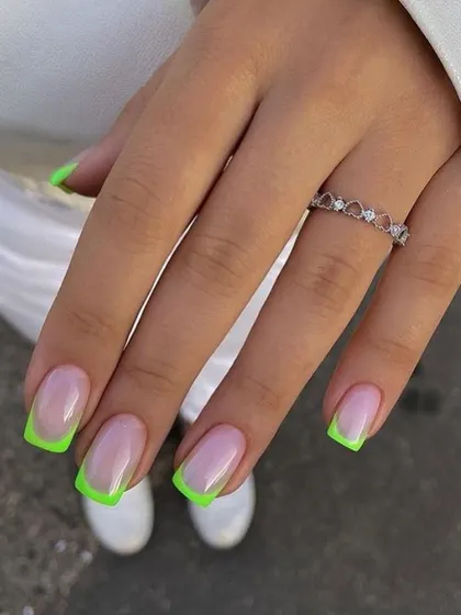 A bold and modern take on the French manicure, featuring square-shaped nails with bright, neon green tips.