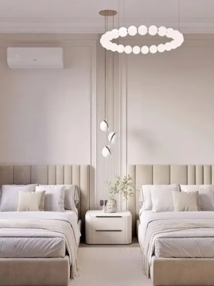 Clean lines and a soft, creamy color palette define this serene shared bedroom. We used vertically paneled headboards and a modern circular chandelier to add texture and interest to the minimalist design.