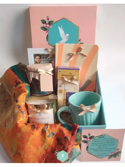 Celebrate a work anniversary with a thoughtful and personalized gift hamper. This one includes a custom photo frame, a beautiful scarf, a scented candle, and other treats to mark the milestone.