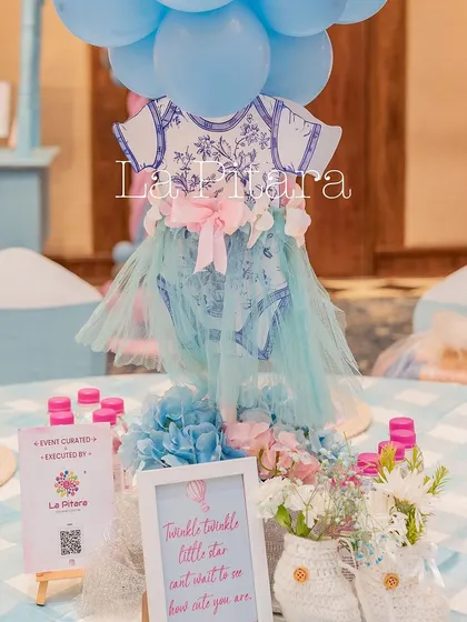 A creative table centerpiece featuring a miniature baby onesie with a tulle skirt, designed with the blue Dior pattern.