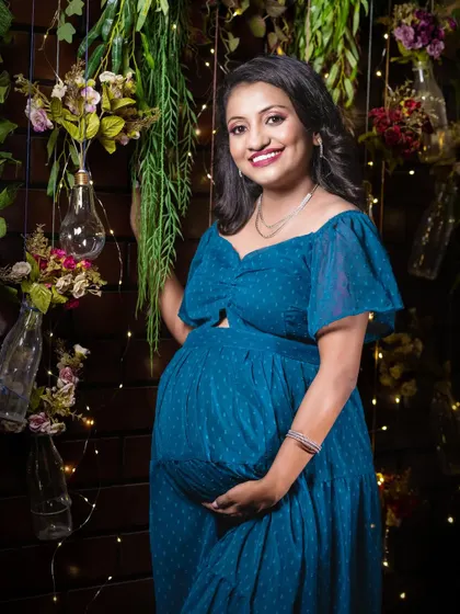 A bright, smiling portrait in the same charming, rustic studio setup. This shot perfectly captures the joy and radiance of the mother-to-be.