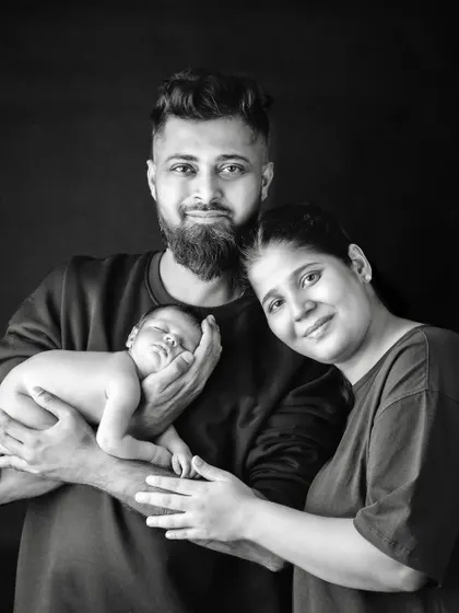 A beautiful black and white portrait of a new family of three. The parents' smiles reflect the immense joy their new baby has brought them.
