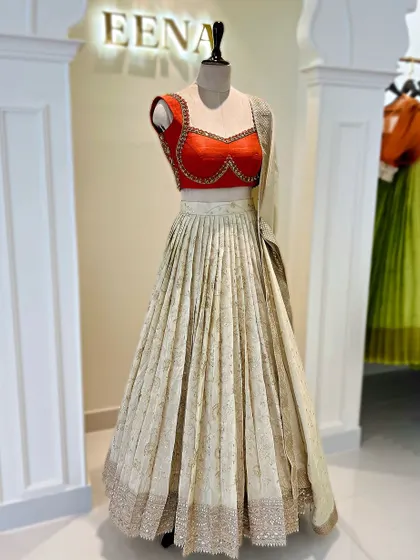 Elegance in every fold. This ivory tissue lehenga with a subtle gold print is paired with a vibrant red katori blouse. The contrast creates a look that is both traditional and incredibly chic.