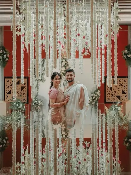 The couple posing for a photo, framed by beautiful hanging floral strings at their wedding.
