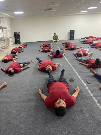 A wide view of a corporate session where employees are in Savasana (Corpse Pose). This final resting pose is crucial for integrating the benefits of the practice, and I ensure there is ample time for it in every session.