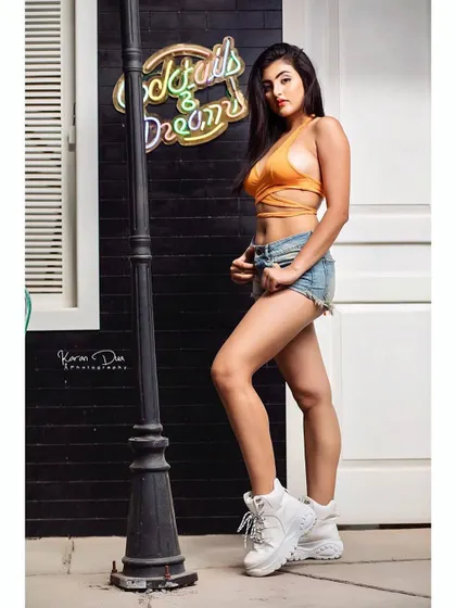 A full-body shot showcasing a modern, urban look. The makeup is kept clean and defined to complement the casual styling and neon sign backdrop, demonstrating versatility for different shoot concepts.