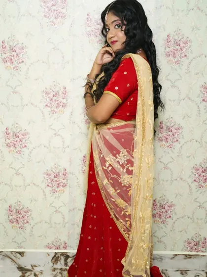 A side profile view of the red lehenga, highlighting the way the gold dupatta drapes over the shoulder.