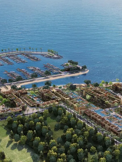 A wide aerial shot of a coastal resort, showing the entire property from the tennis courts and residential blocks to the marina and surrounding ocean.