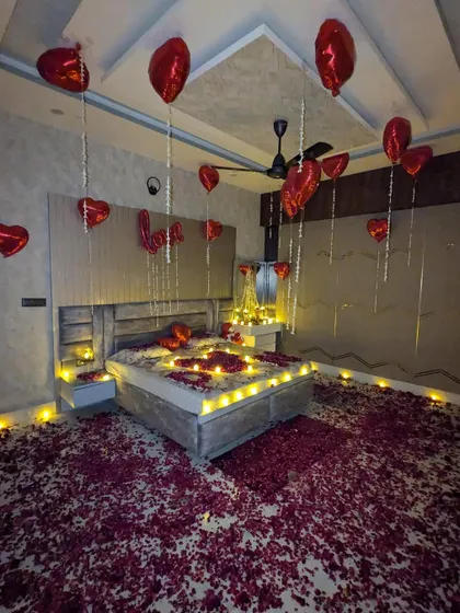 Another angle of a surprise room decoration, showing how the combination of floating balloons and a floor covered in petals instantly creates a festive and romantic mood.