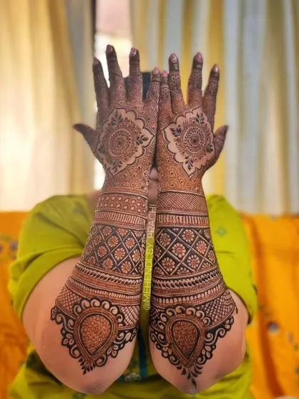 This is the back of a bridal mehndi design, which is just as important as the front. It features beautiful mandala work on the back of the hand with heavy, intricate patterns on the arms.
