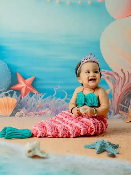 This wide shot shows the full scale of the mermaid set, complete with giant pearls, coral, and a sandy beach.