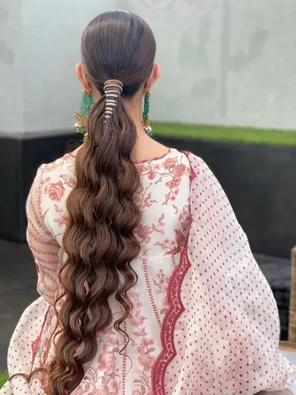 This is a long, wavy ponytail wrapped with a diamond string accessory. It’s a very chic and elegant way to style a ponytail for a wedding or special event.