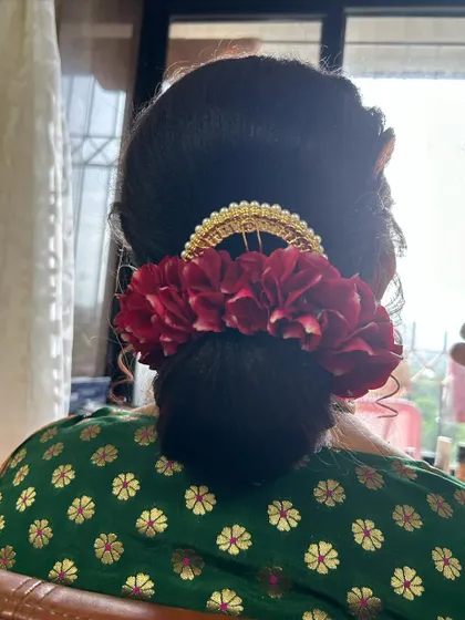 The final look of the apple bun with a red floral accessory. It’s a timeless and graceful hairstyle.