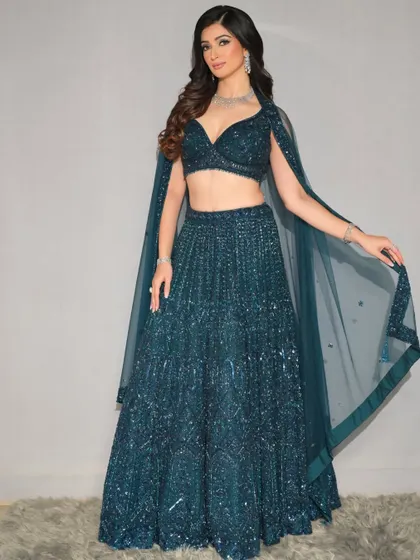 A full-length shot of the sparkling blue lehenga. The makeup is designed to match the glamour and elegance of the outfit.