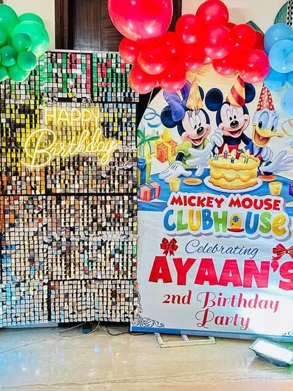 A close-up of the Mickey Mouse Clubhouse birthday setup, showing the character banner and rainbow-colored balloon clusters.