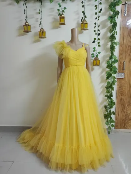 A bright and cheerful yellow tulle gown with a one-shoulder ruffle detail. This is a perfect rental for a summer event or photoshoot.