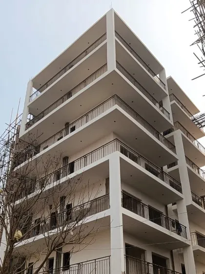 A nearly completed apartment building, showing the clean white facade and the rhythm of the wrap-around balconies. This is a prime example of modern urban housing.