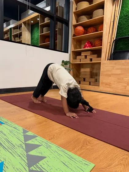 A young student practices Adho Mukha Svanasana, or Downward-Facing Dog. It's a fundamental pose we teach to help kids build upper body strength and stretch their hamstrings.