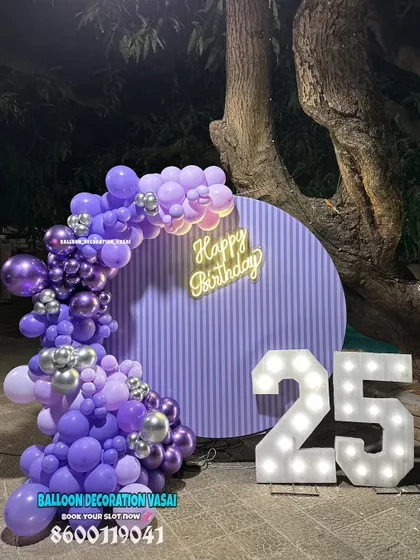 A 25th birthday party with a purple and silver theme. This outdoor setup with a striped backdrop and marquee numbers looks stunning at night.