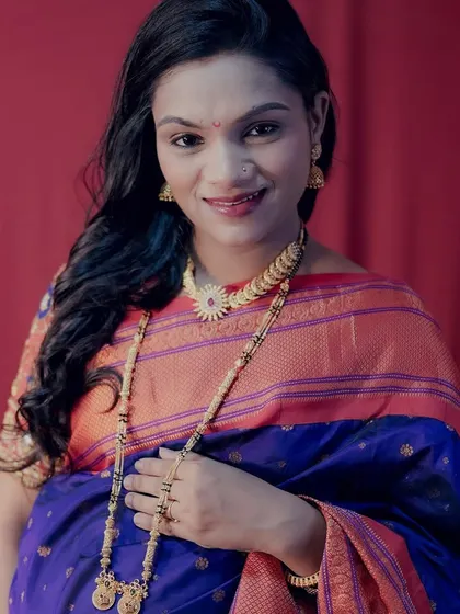 A stunning portrait of a mom-to-be in a traditional blue and orange saree, complete with beautiful gold jewellery.