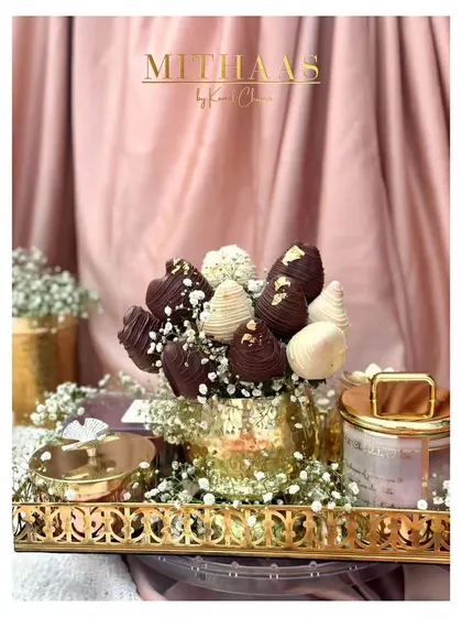 A romantic and luxurious gift arrangement. A bouquet of chocolate-covered strawberries sits in a golden vase on an ornate tray, perfect for Valentine's Day or an anniversary.
