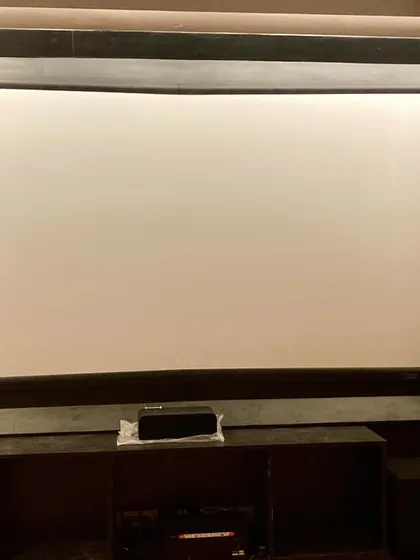 The front view of a dedicated home theater in Firozabad. This setup includes a fixed-frame screen and floor-standing speakers, delivering powerful and clear audio for an authentic movie experience.