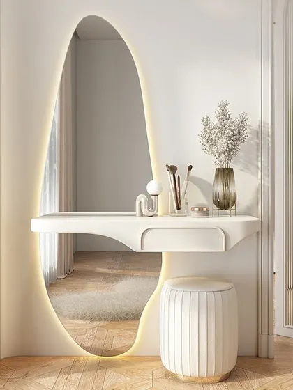 A sleek and modern dressing mirror design. The oval mirror with integrated backlighting and a minimalist floating shelf creates an elegant and functional vanity space.