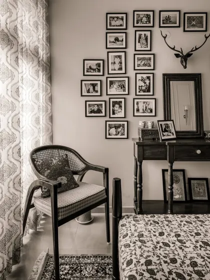 A cozy corner in the 'Heritage Hue' bedroom, featuring a classic wooden chair with cane details, a console table, and a gallery wall of cherished family photos, creating a space full of memory and warmth.