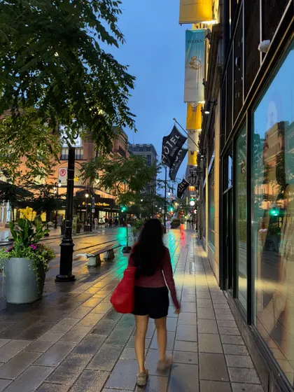 Walking down a wet sidewalk in downtown Montréal, with reflections of the city lights all around.