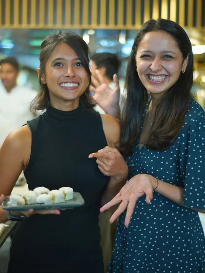 The joy of accomplishment. Two participants laugh as they show off the perfect sushi rolls they just made during our hands-on workshop.