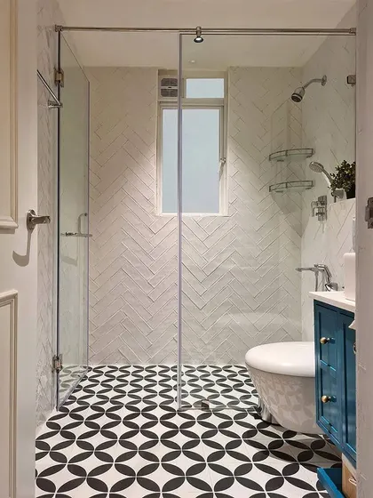 This master bathroom from the Breeze Home project shows how to pack big design moments into a small space. The glass shower enclosure keeps the room feeling open, while the contrast between the herringbone wall tile and the geometric floor tile creates visual excitement.