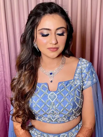 The soft waves perfectly complement the delicate embroidery on her blue lehenga.