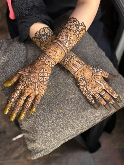 A complete view of a matching set of bridal mehendi. The design is consistent across both hands and arms, featuring a beautiful arch on the palm and detailed bands on the forearm.