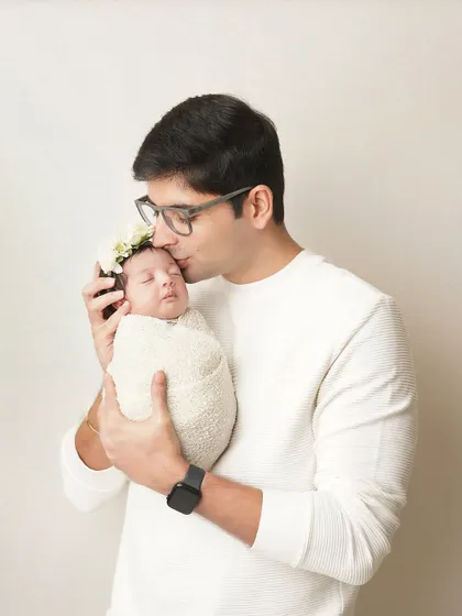 A father gives his sleeping newborn a gentle kiss on the forehead. It's these small, tender gestures that tell the biggest stories of love.